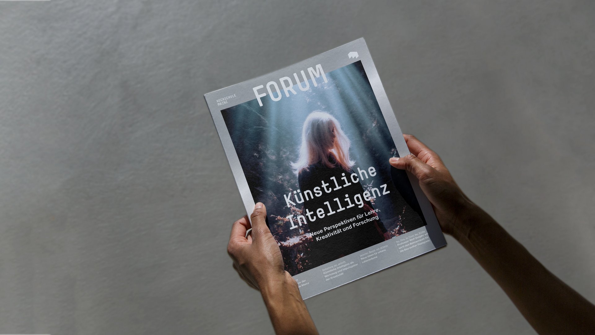 Eine Person hält die aktuelle Ausgabe des Hochschulmagazins FORUM der Hochschule Mainz mit dem Schwerpunktthema „Künstliche Intelligenz“ in den Händen.
