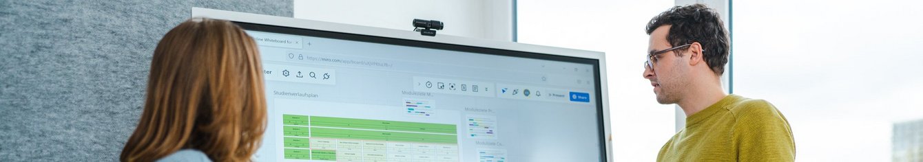 Zwei Personen erklären etwas an einem digitalen Bildschirm