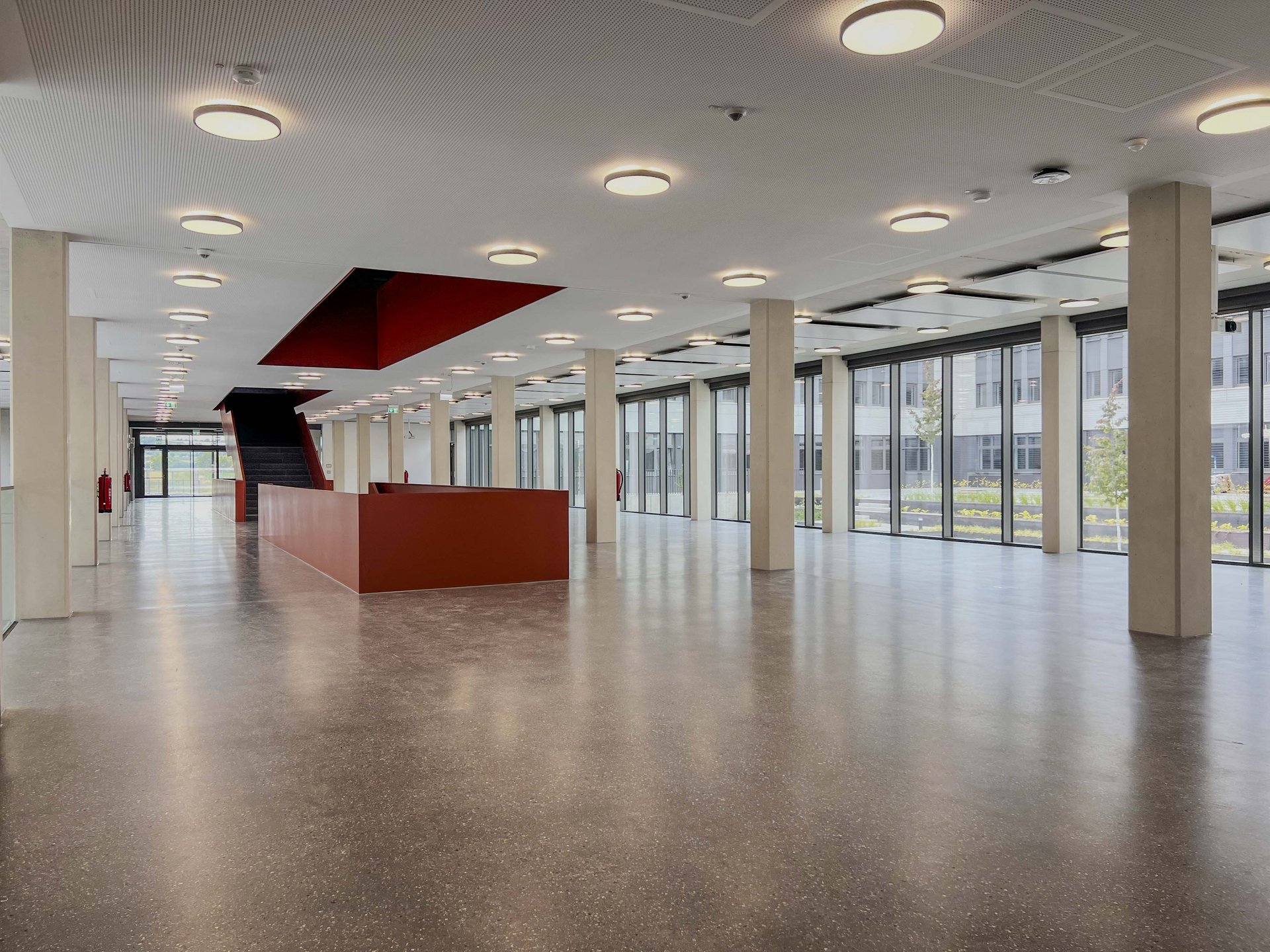 Blick durch die lichtdurchflutete Magistrale des neuen Campus der Hochschule Mainz mit Treppenanlage und großzügigen Aufenthaltsflächen.
