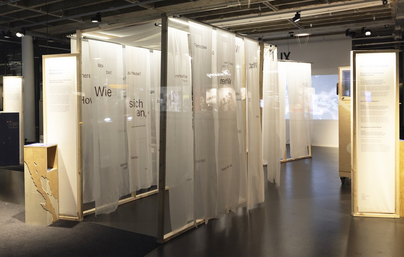 Ausstellung mit transparenten Stoffbahnen und Informationstafeln